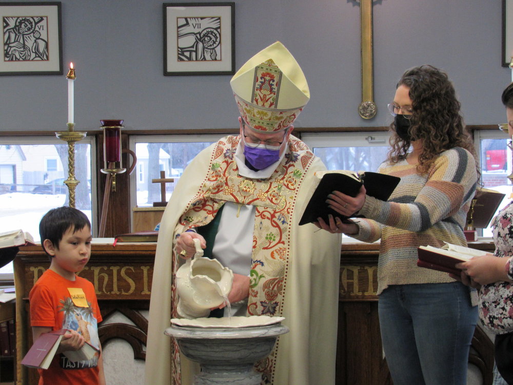 Bishop folts with parishoners preparing for baptism